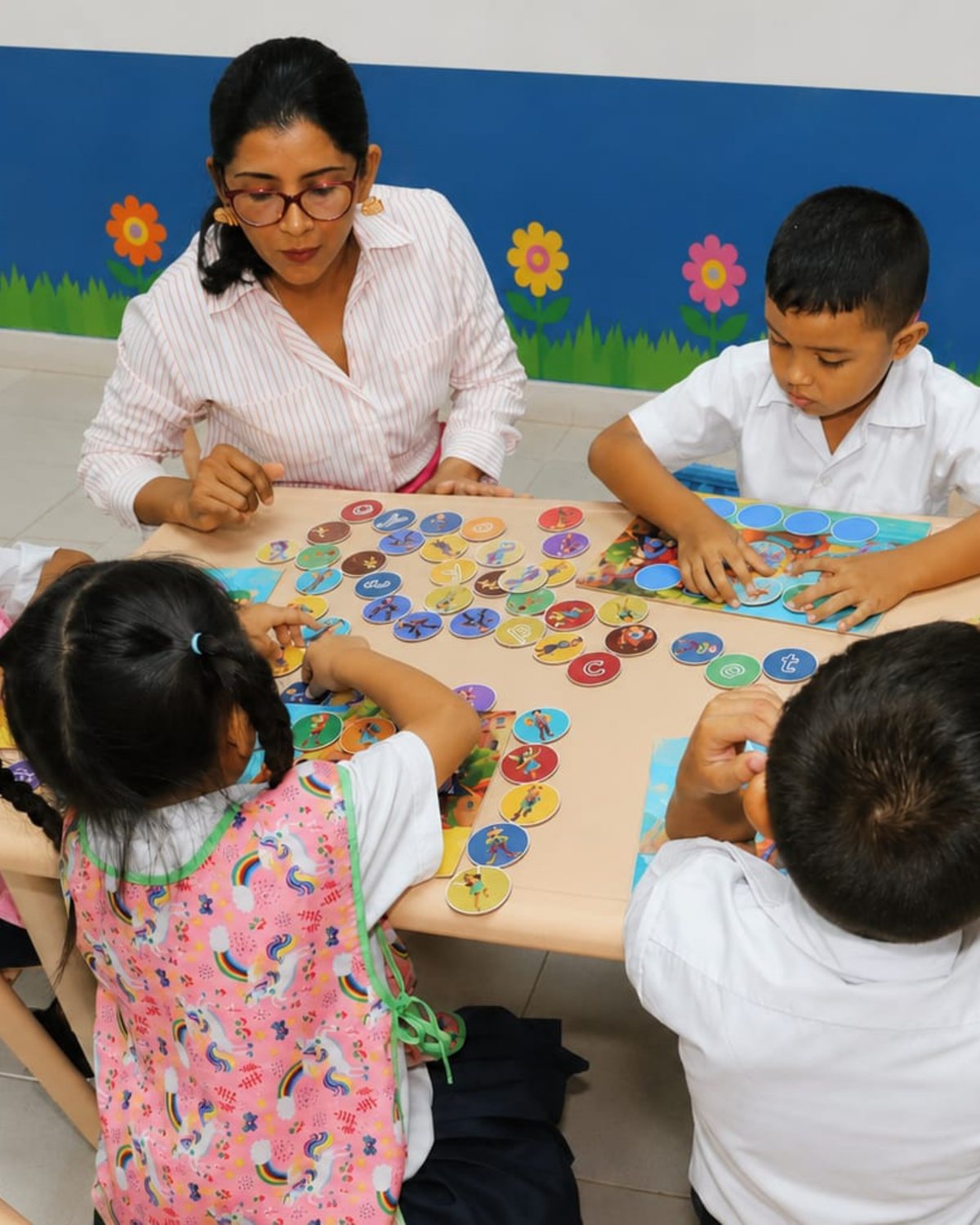 La guía acompaña a cuatro niños que colocan las fichas de las letras sobre la mesa