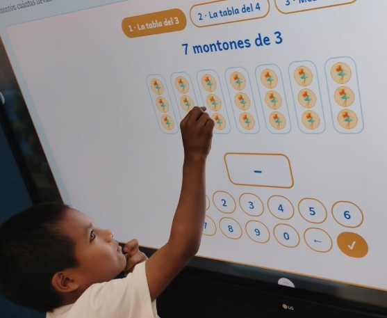 Un niño resuelve en la pantalla del aula la actividad Montones: siete montones de tres