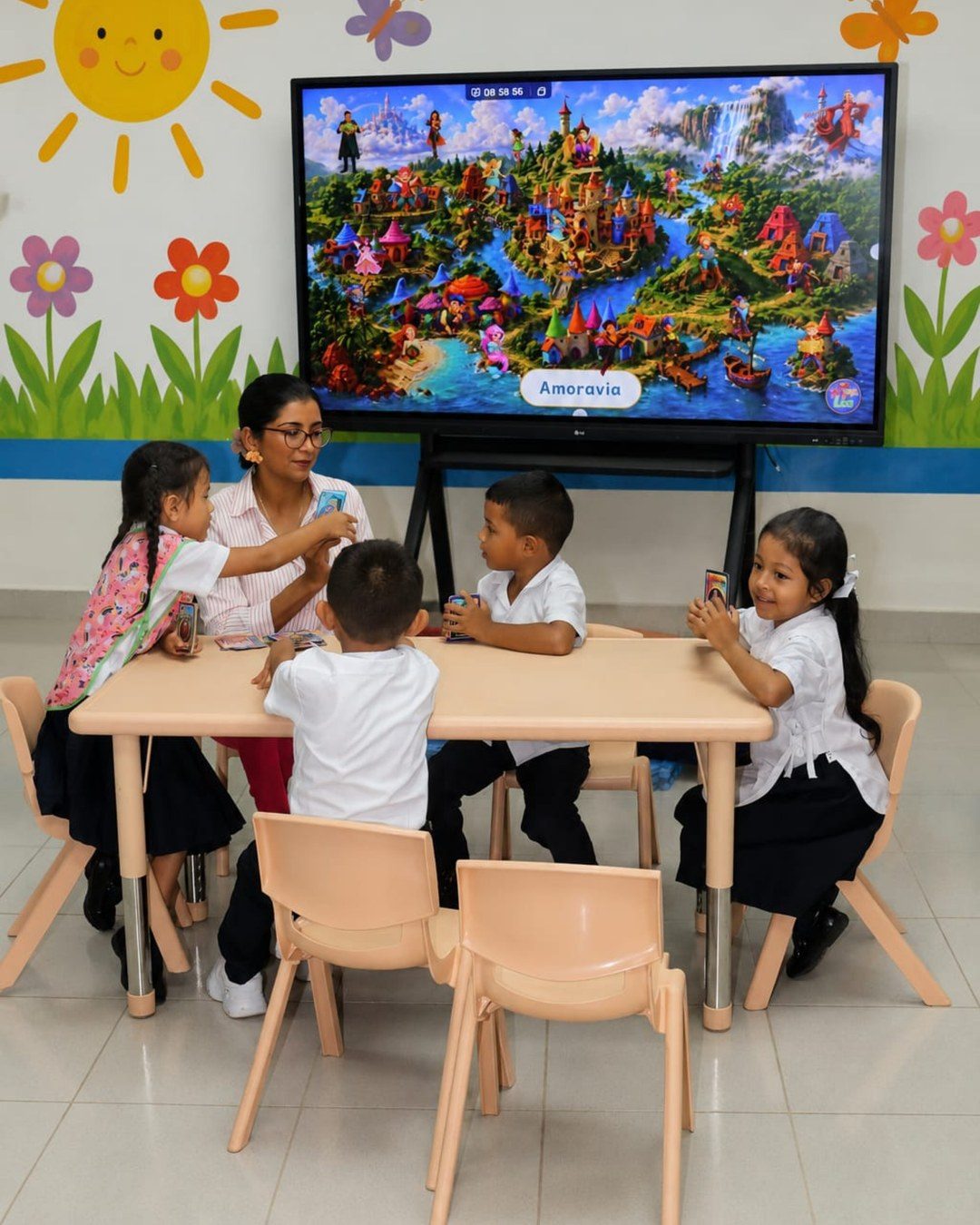 Dayana Pitty trabajando con cuatro niños frente a la pantalla con el mapa de Amoravia