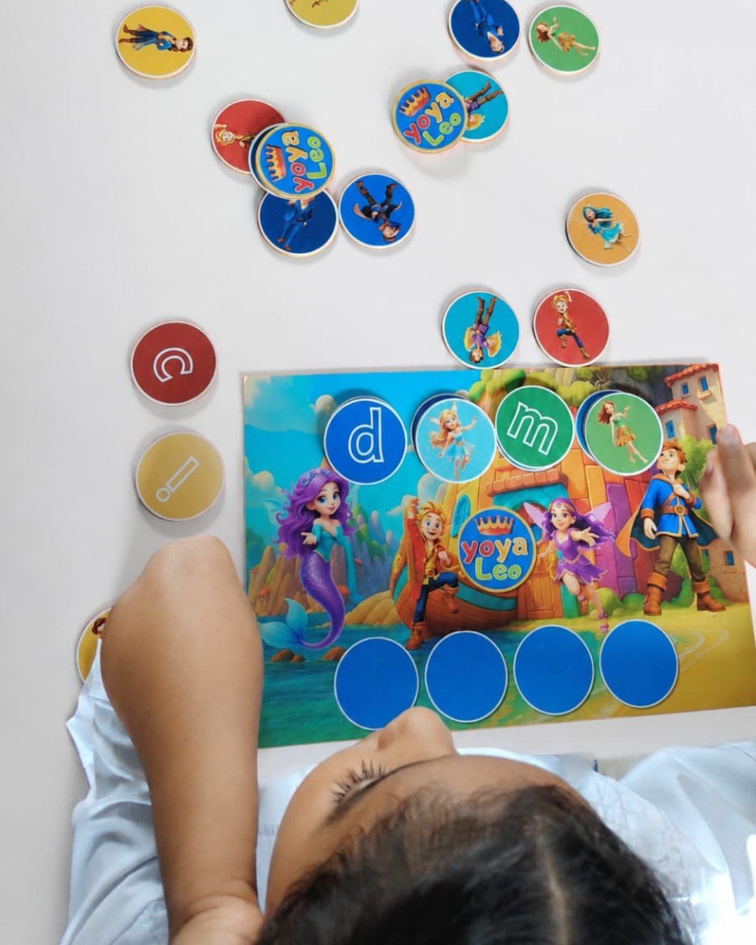 Tablero y fichas de Yoya y Leo: un niño coloca las letras junto a sus personajes