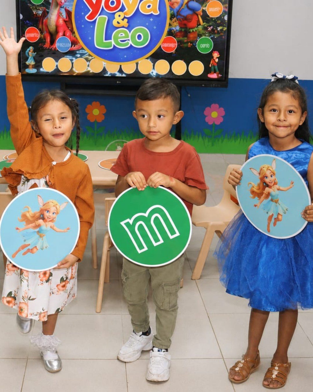Tres niños sosteniendo las fichas grandes de las letras y sus personajes